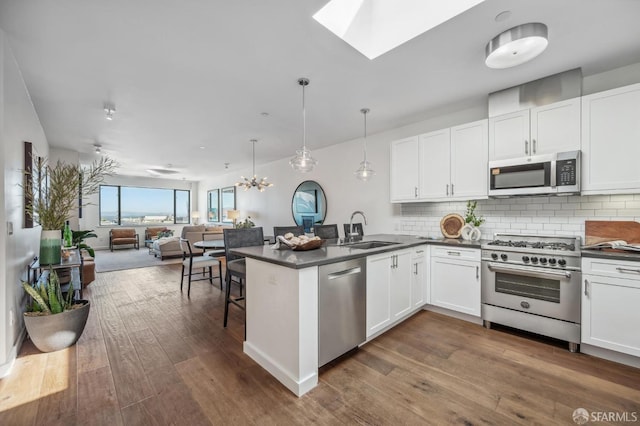 kitchen featuring hanging light fixtures, stainless steel appliances, kitchen peninsula, and white cabinets