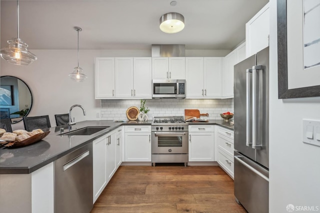 kitchen featuring high end appliances, white cabinets, tasteful backsplash, and pendant lighting