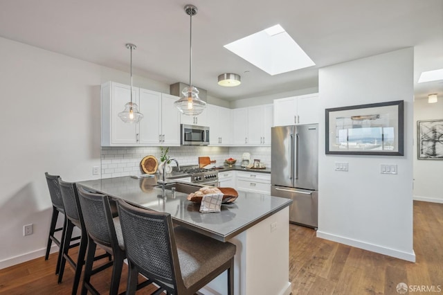 kitchen with high end appliances, decorative light fixtures, kitchen peninsula, and white cabinets