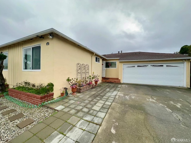 view of side of property with driveway, a garage, and stucco siding