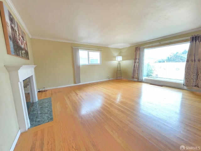 unfurnished living room with a high end fireplace, crown molding, baseboards, and wood finished floors