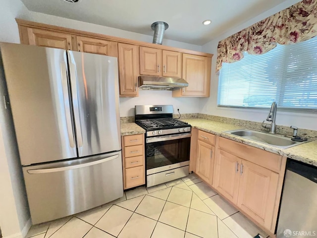 kitchen with light tile patterned floors, appliances with stainless steel finishes, light brown cabinets, a sink, and under cabinet range hood