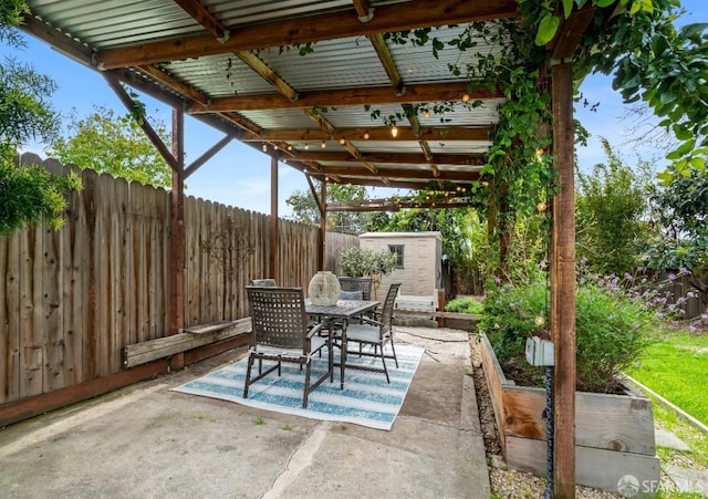 view of patio featuring an outbuilding, outdoor dining area, a vegetable garden, a storage unit, and a fenced backyard