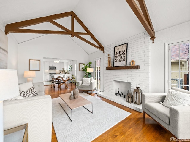 living room featuring a brick fireplace, high vaulted ceiling, wood finished floors, and beamed ceiling