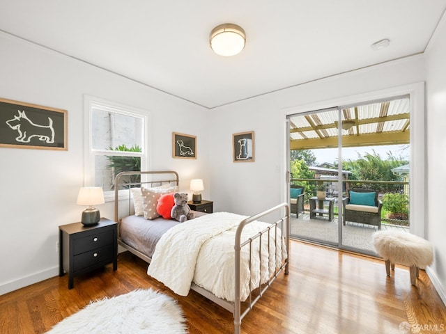 bedroom featuring baseboards, wood finished floors, and access to exterior