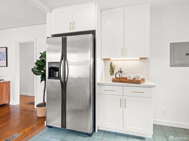 kitchen featuring visible vents, stainless steel fridge, electric panel, and white cabinetry