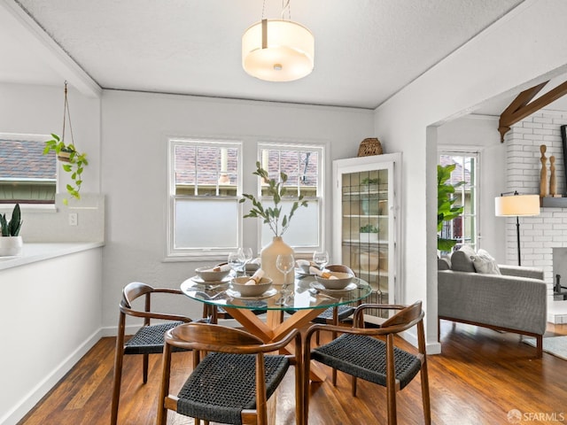 dining space with a healthy amount of sunlight, a fireplace, baseboards, and wood finished floors