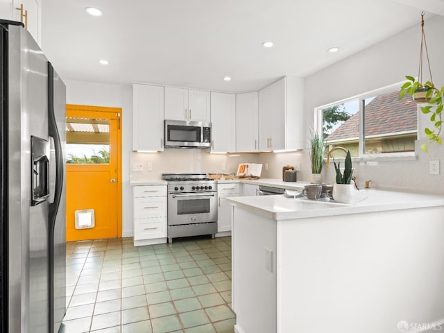 kitchen with a peninsula, light tile patterned floors, stainless steel appliances, and light countertops