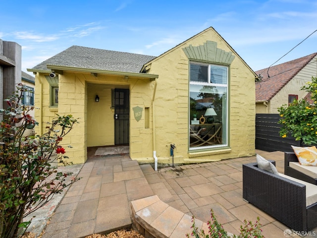 back of house featuring a patio and roof with shingles