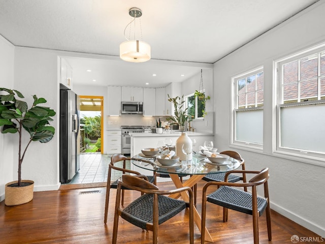 dining area with a wealth of natural light, baseboards, and light wood finished floors