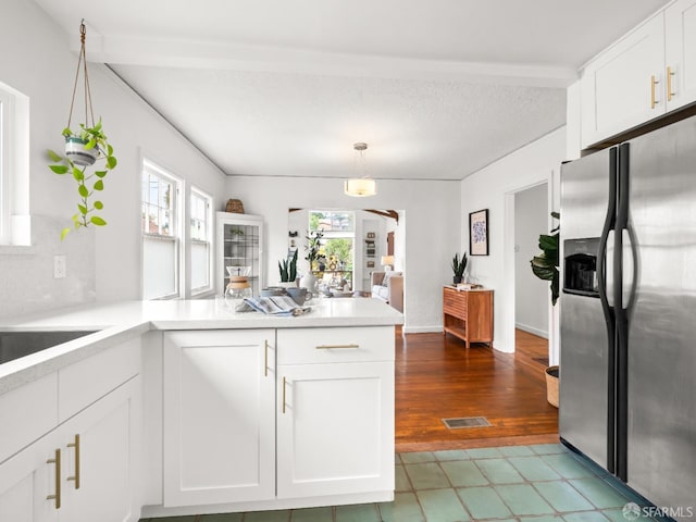 kitchen with a peninsula, visible vents, white cabinets, light countertops, and stainless steel fridge