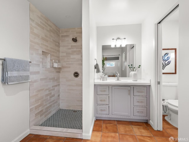 bathroom with tiled shower, vanity, toilet, and tile patterned floors