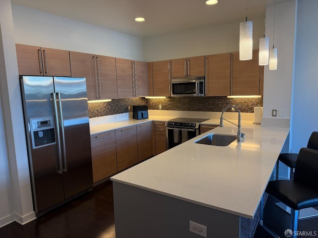 kitchen with appliances with stainless steel finishes, decorative light fixtures, sink, a kitchen breakfast bar, and kitchen peninsula