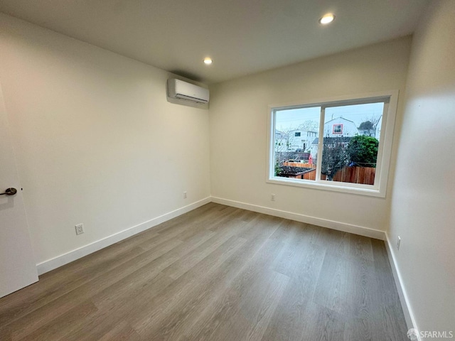 unfurnished room with hardwood / wood-style floors and a wall mounted AC