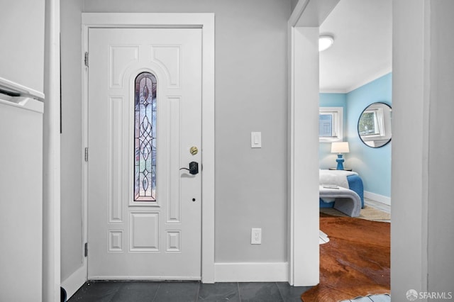 entryway featuring ornamental molding and dark tile patterned floors