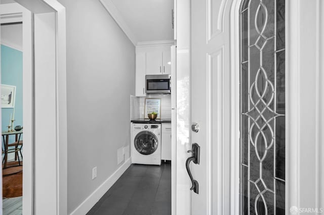 laundry room featuring washer / clothes dryer, ornamental molding, and dark tile patterned floors