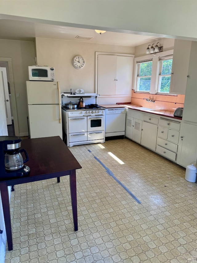 kitchen with white cabinetry, sink, white appliances, and tasteful backsplash