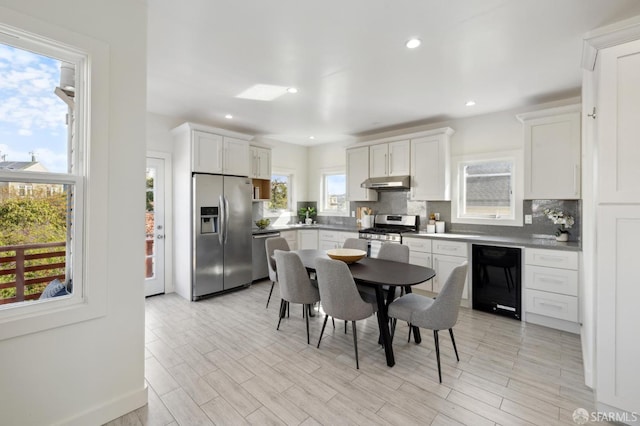 kitchen featuring appliances with stainless steel finishes, white cabinets, light hardwood / wood-style floors, and backsplash