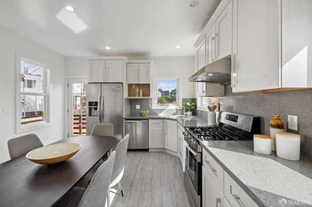 kitchen featuring exhaust hood, appliances with stainless steel finishes, white cabinets, and plenty of natural light