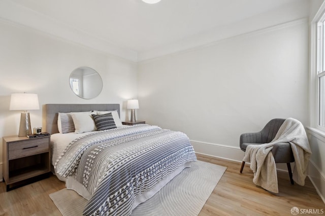 bedroom with light hardwood / wood-style floors and crown molding