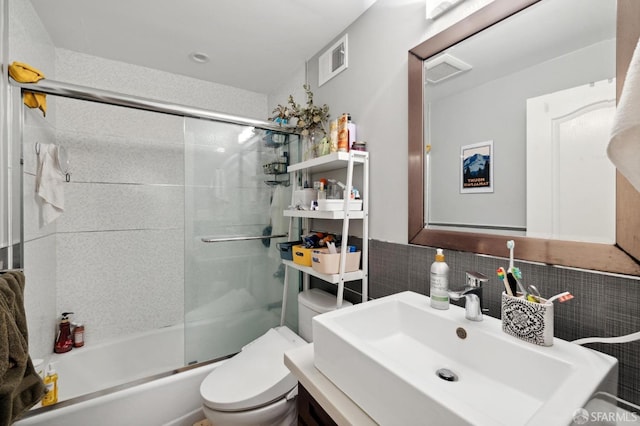 full bathroom featuring backsplash, vanity, combined bath / shower with glass door, and toilet