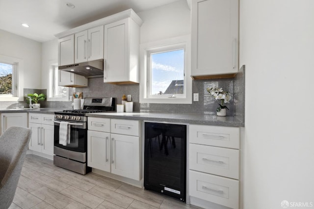 kitchen featuring decorative backsplash, wine cooler, light wood-type flooring, white cabinets, and gas stove