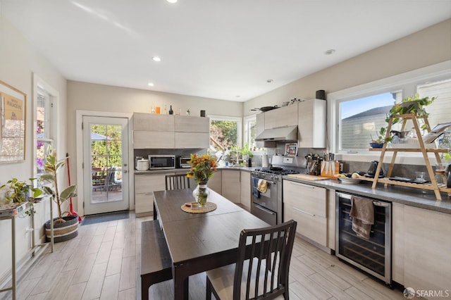 kitchen with extractor fan, a healthy amount of sunlight, stainless steel appliances, and beverage cooler