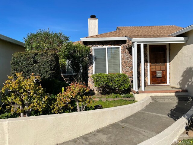 21723 Ada St, Castro Valley, CA 94546 - view of exterior entry with stone siding, a chimney, and stucco siding