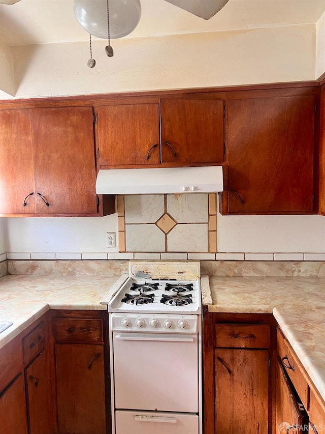933 41st St, Oakland, CA 94608 - kitchen with under cabinet range hood, white range with gas cooktop, tasteful backsplash, and light countertops