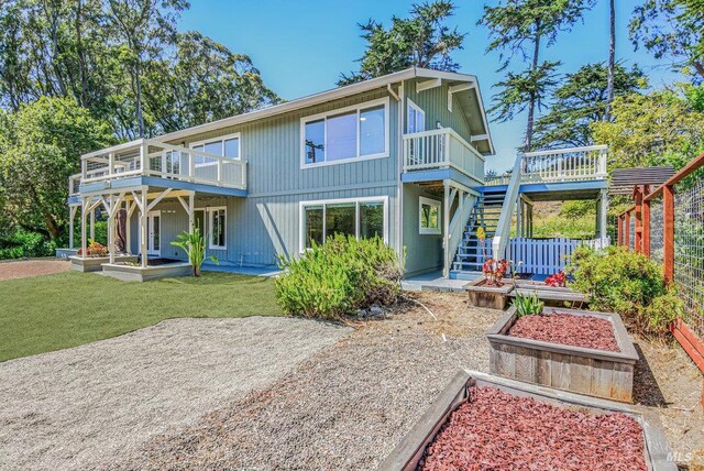 1685 Bay Flat Rd, Bodega Bay, CA 94923 - back of property featuring a vegetable garden, stairs, a deck, and a lawn