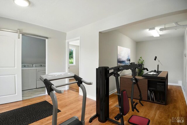 1685 Bay Flat Rd, Bodega Bay, CA 94923 - exercise area with washer and clothes dryer, wood finished floors, baseboards, and a barn door