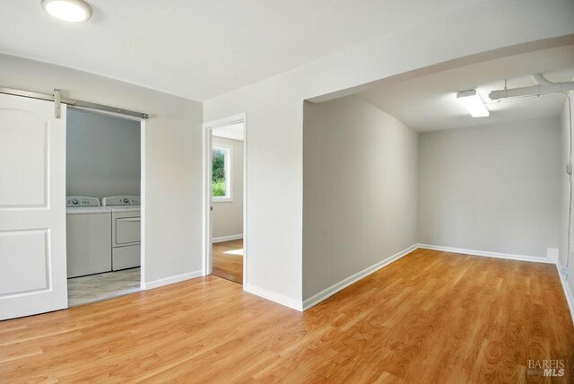 1685 Bay Flat Rd, Bodega Bay, CA 94923 - spare room featuring washer and dryer, light wood-style flooring, baseboards, and a barn door
