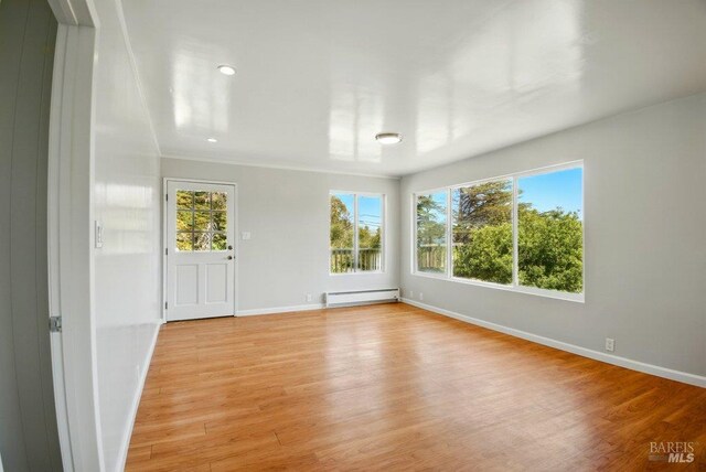 1685 Bay Flat Rd, Bodega Bay, CA 94923 - unfurnished room with a baseboard heating unit, light wood finished floors, and baseboards