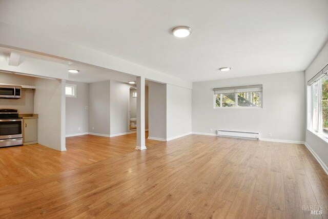 1685 Bay Flat Rd, Bodega Bay, CA 94923 - unfurnished living room featuring a baseboard radiator, light wood-type flooring, and baseboards