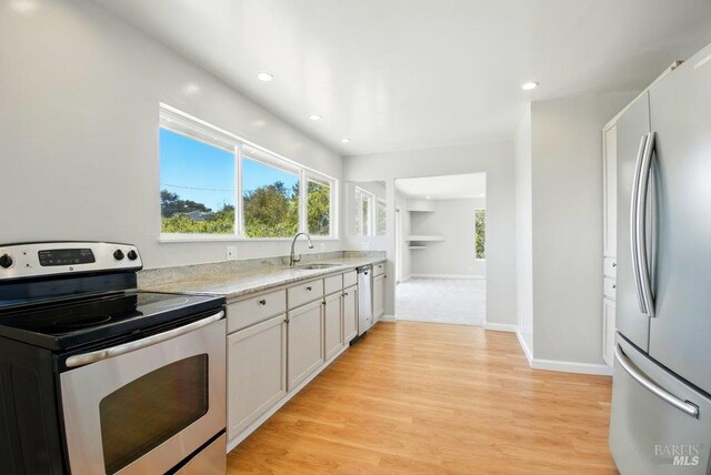 1685 Bay Flat Rd, Bodega Bay, CA 94923 - kitchen featuring stainless steel appliances, a sink, light countertops, light wood-type flooring, and white cabinetry