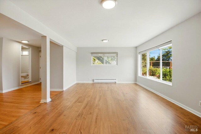 1685 Bay Flat Rd, Bodega Bay, CA 94923 - unfurnished living room featuring baseboard heating, light wood-style flooring, and baseboards