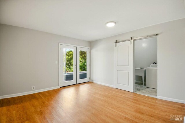 1685 Bay Flat Rd, Bodega Bay, CA 94923 - unfurnished room with a barn door, light wood-style flooring, and baseboards