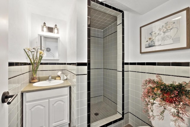 bathroom featuring vanity, tile walls, wainscoting, and a shower stall