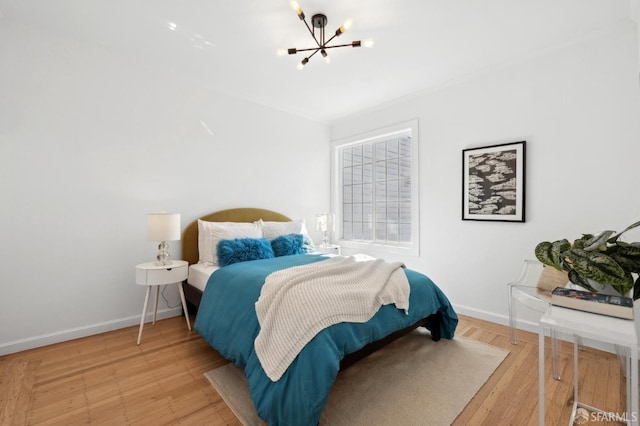 bedroom featuring crown molding, a notable chandelier, baseboards, and light wood-type flooring