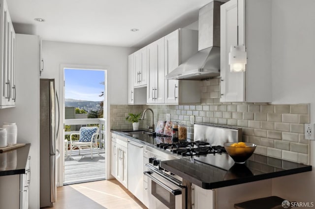 kitchen featuring dark countertops, tasteful backsplash, wall chimney range hood, dishwasher, and a sink