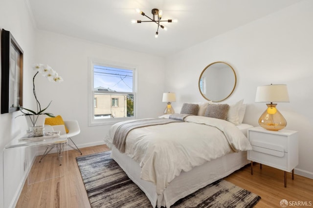 bedroom with baseboards, an inviting chandelier, and wood finished floors