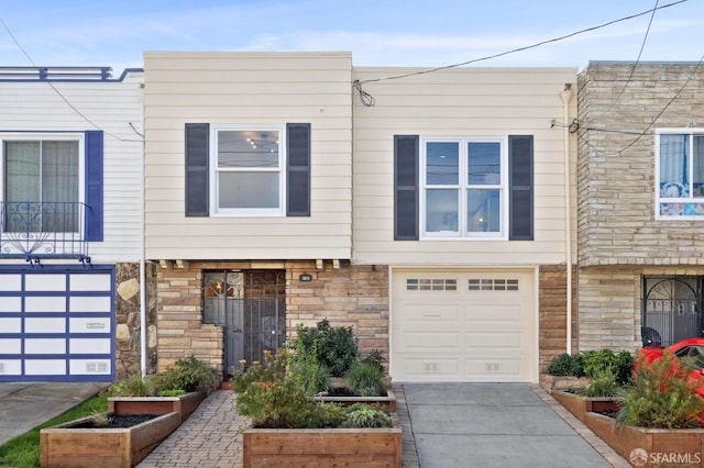 multi unit property with concrete driveway, an attached garage, and stone siding