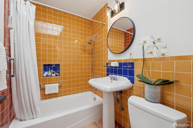 bathroom with a wainscoted wall, toilet, tile walls, and shower / tub combo