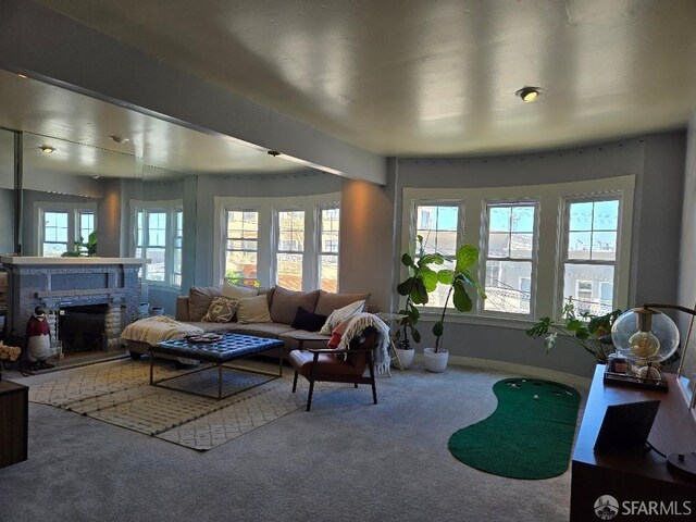 carpeted living area featuring a fireplace with raised hearth, baseboards, and a healthy amount of sunlight