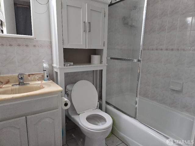 full bathroom featuring vanity, shower / bath combination with glass door, toilet, tile walls, and tile patterned floors