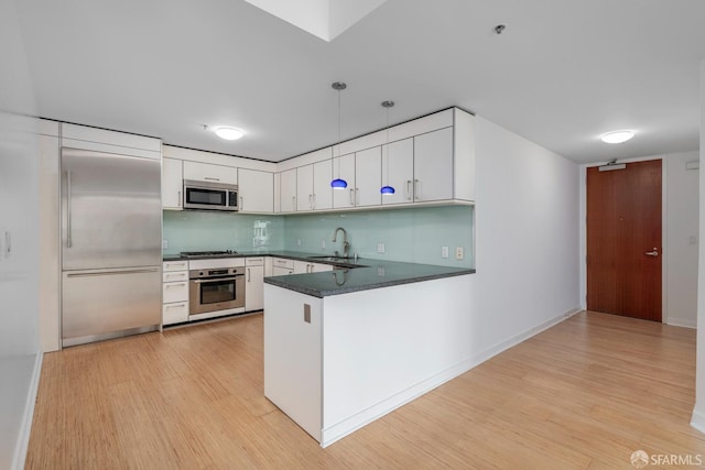 kitchen with pendant lighting, kitchen peninsula, appliances with stainless steel finishes, and white cabinets