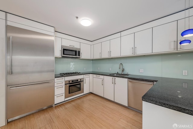 kitchen featuring stainless steel appliances, white cabinetry, sink, and light wood-type flooring