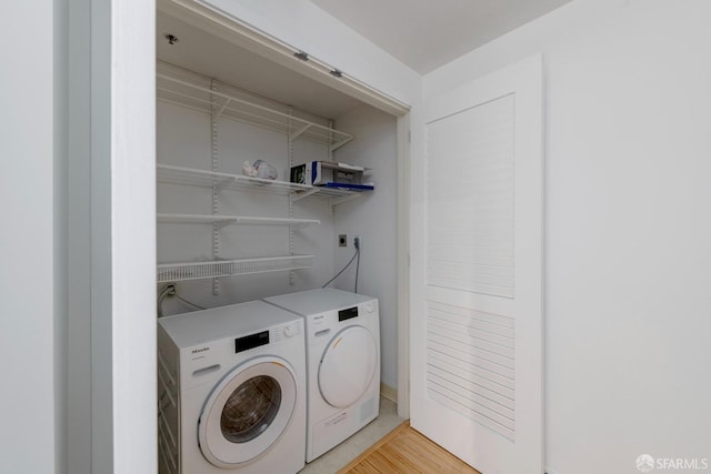 washroom featuring washing machine and dryer and light hardwood / wood-style flooring