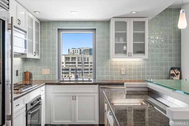 333 1st St Unit N1404, San Francisco, CA 94105 - kitchen featuring appliances with stainless steel finishes, white cabinetry, glass insert cabinets, dark stone counters, and recessed lighting