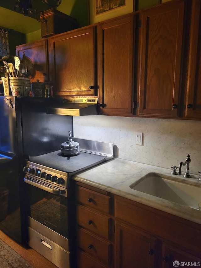 kitchen featuring under cabinet range hood, stainless steel electric range, light countertops, and a sink